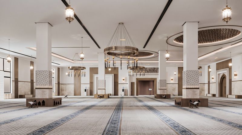 Prayer hall of the masjid, with brass lanterns and rows of prayer rugs